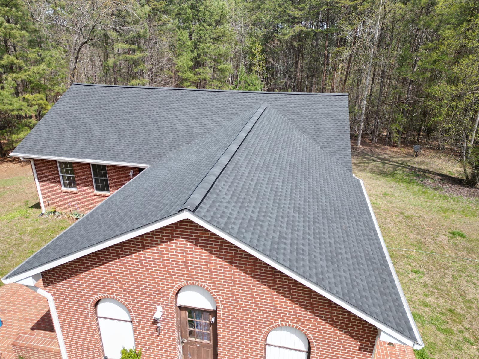 Aerial view of a Charlottesville-area brick home with new dark architectural shingles